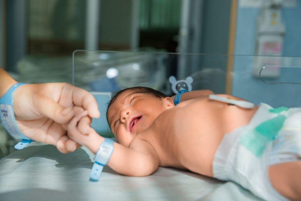 father holds hand of newly born baby in diapers
