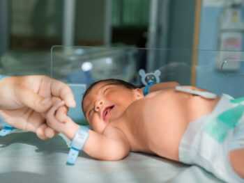 father holds hand of newly born baby in diapers